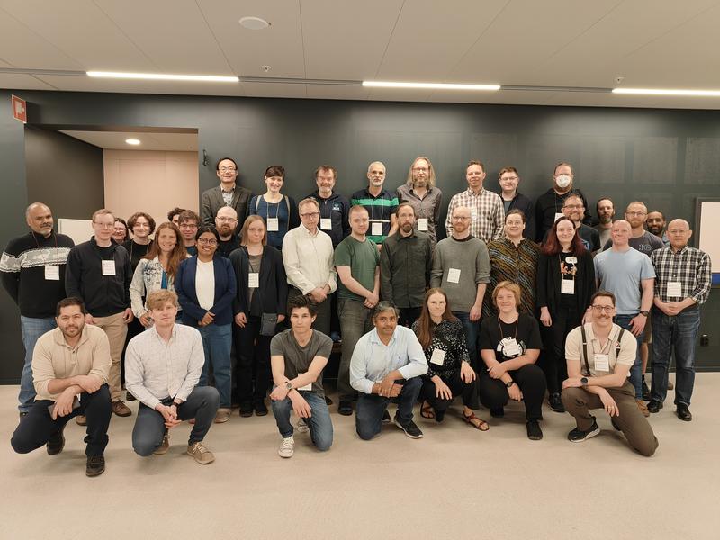 A group photo of about forty research software engineers stood or knelt for a group photo inside a building.