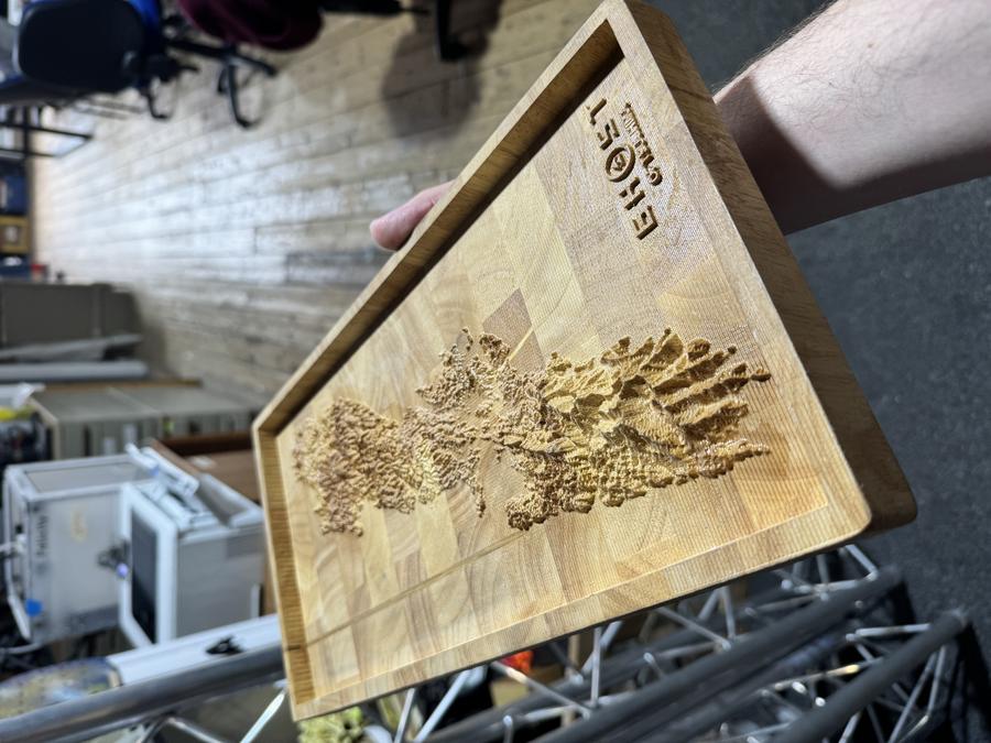 A photo of me holding a wooden block into which a mountain range has been carved