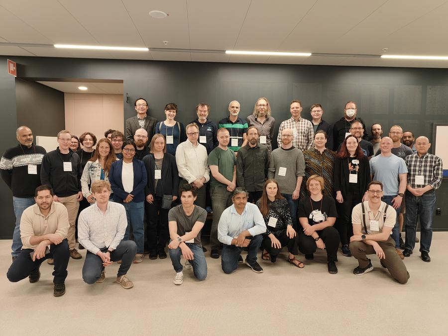 A group photo of about forty research software engineers stood or knelt for a group photo inside a building.