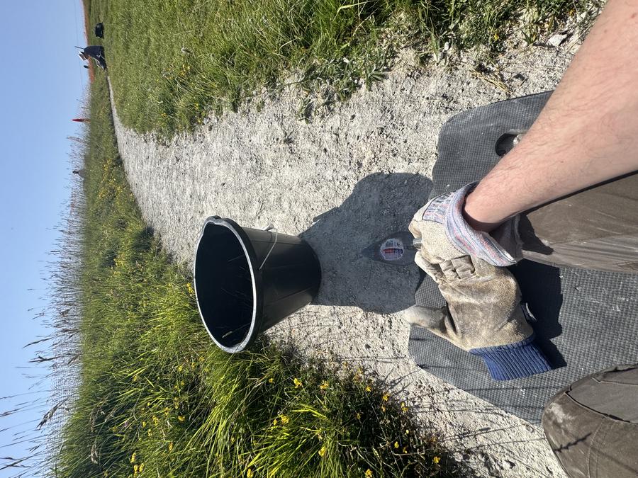 A first person view photograph of weeding the horse: you can see my bucket, my knees on a foam pad, and a trowel in my hand.